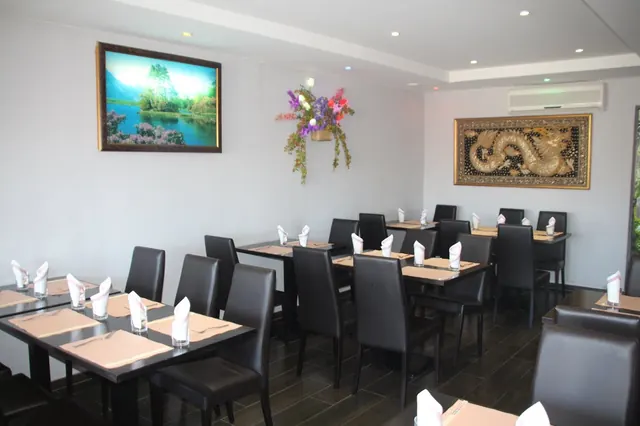 La salle : tables dressées, chaises noires, tableau de dragon au mur